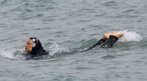 Woman in burkini swimming in beach 