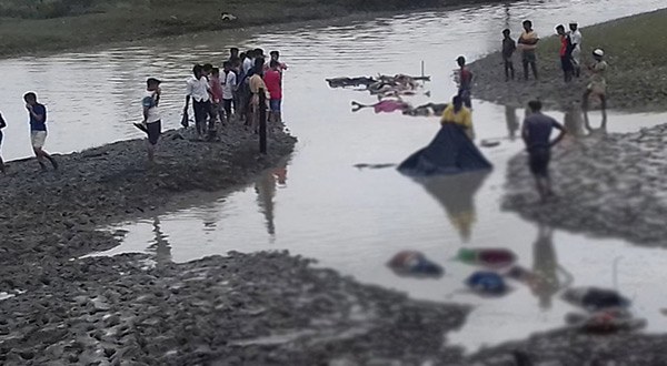 Bangladeshi onlookers stand next to the bodies of Rohingya refugees that washed up during low tide on September 1, 2017 after their boat capsized 